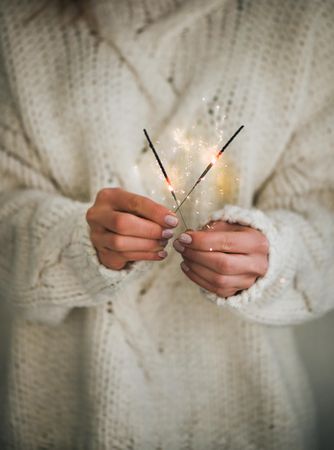 Woman holding two sparklers,  sweater, square crop