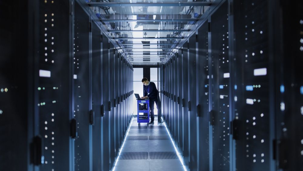 IT Engineer With Crash Cart Puts Hard Drives into Open Rack Server Cabinet.
