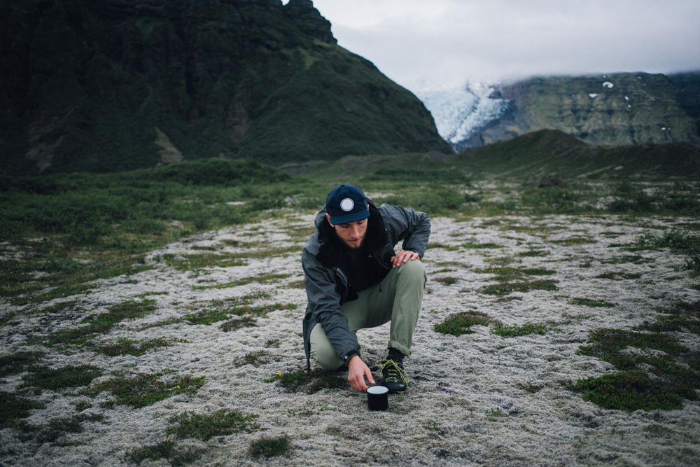 Man with ceramic mug on overcast day while out hiking