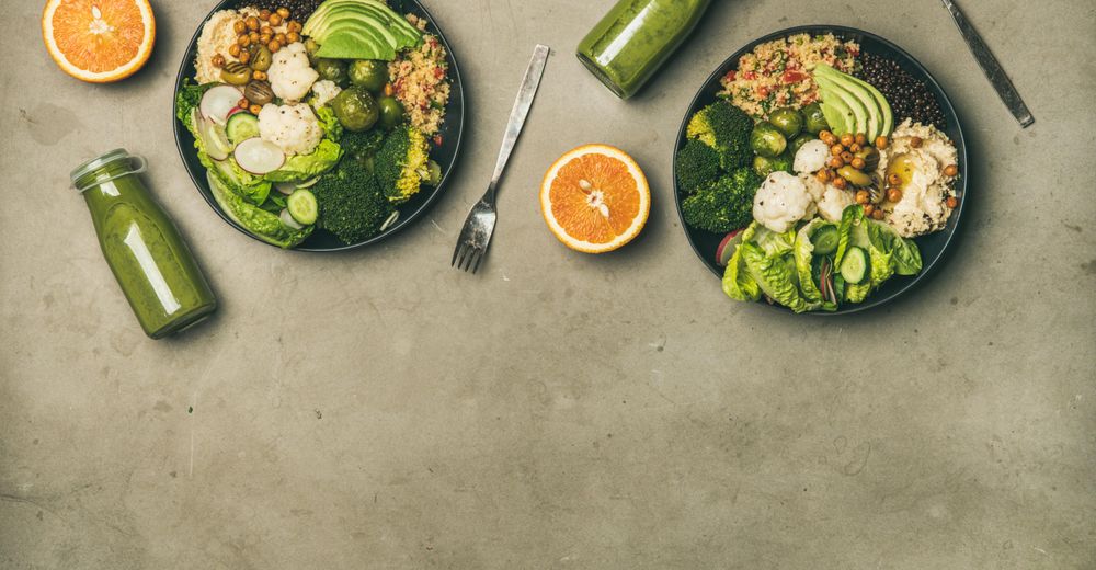 Two vegetarian bowls, with smoothie, orange halves, silverware, with copy space
