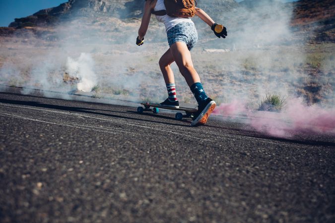 Cropped image of young woman skateboarding on a road