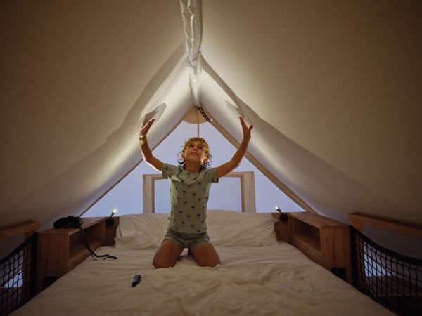 Cute boy touching ceiling on bed