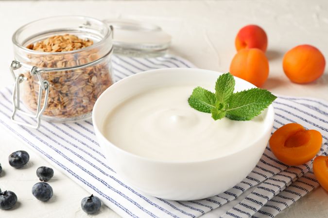 Composition with granola, yogurt and fresh fruits on cement background