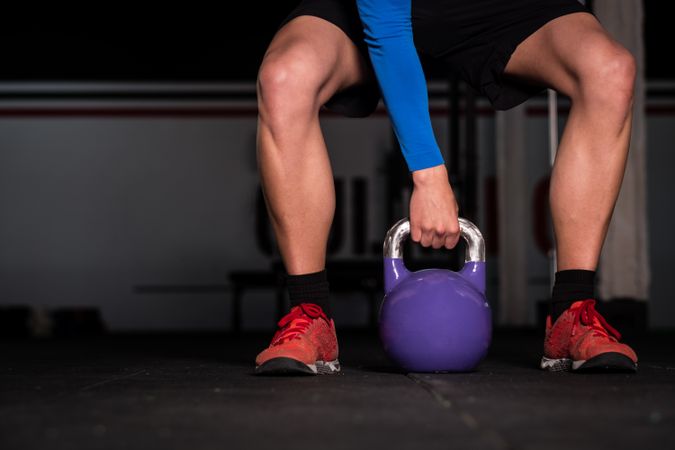 Man holding kettlebell on floor in gym