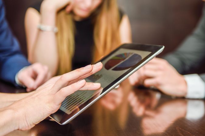 Close up of corporate colleagues using digital tablet during a meeting