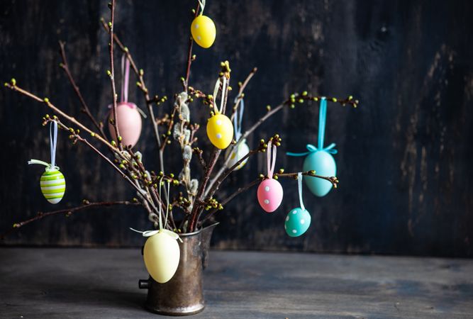 Branches in vase decorated with pastel egg on table