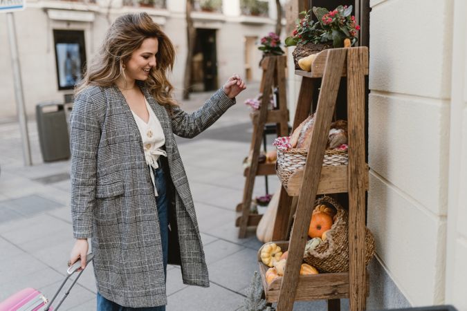 Smiling female tourist near grocery shop