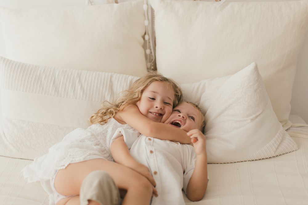 Sister embracing little brother at home