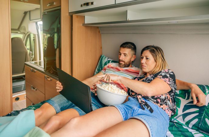 Male and female enjoying a film on a digital tablet on a motorhome bed