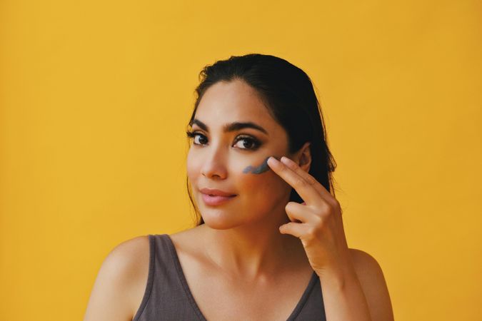 Content Latina woman applying clay mask with hand, copy space