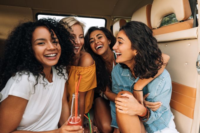 Four friends smiling in the back of a van