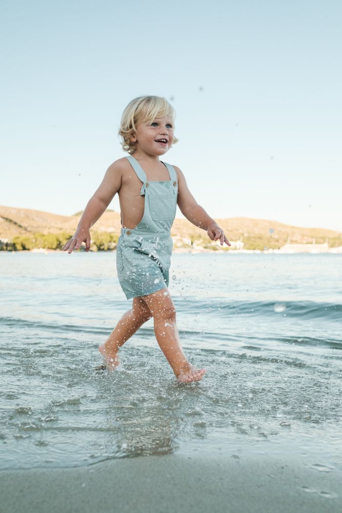 Happy little toddler splashing and promenading in sea under clou