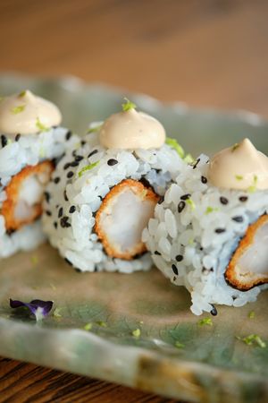 Delicious sushi rolls on plate placed on wooden table