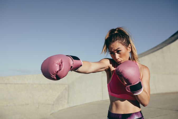 Sportswoman training boxing outdoors