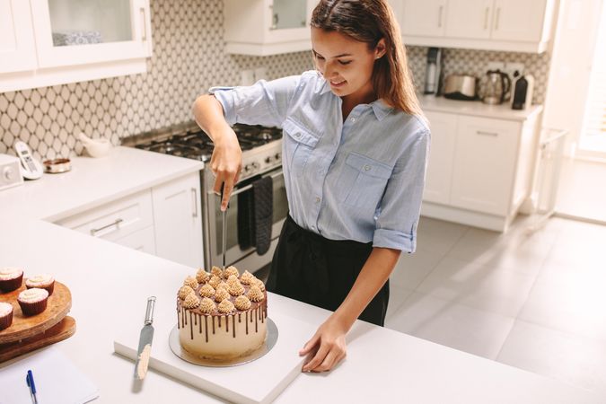 Female chef cutting freshly prepared cake in kitchen