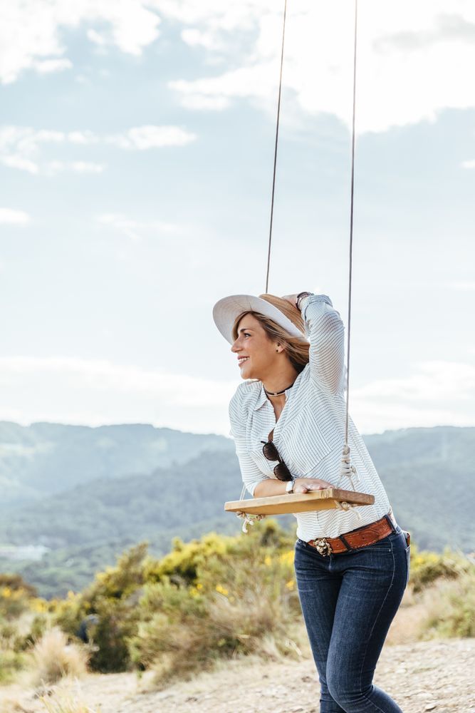 Happy woman with hat next to a swing