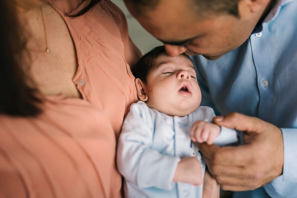 Happy family holding baby and standing at home together