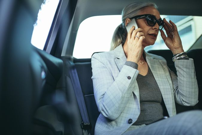 Older female entrepreneur traveling to work in a luxury car