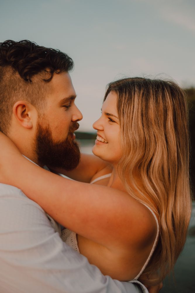 Loving man carrying happy woman on hands on shore
