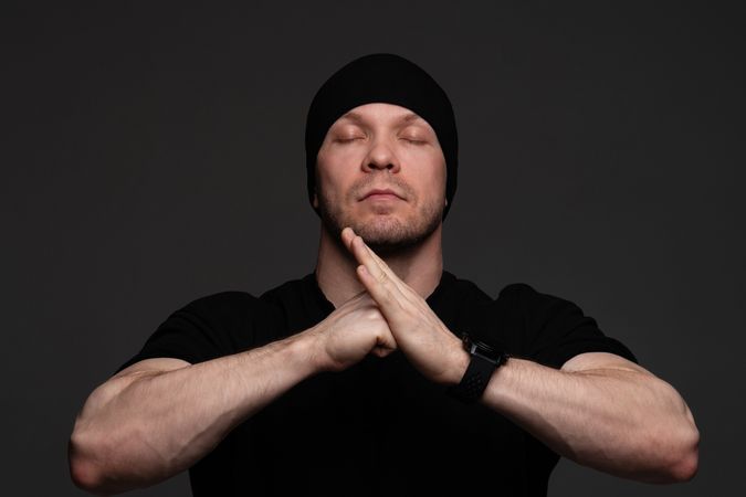 Man in beanie and sweatshirt meditating with hands together