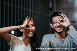 Asian couple circling eye with hand for photo 0V66eD