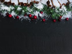 Christmas top border on dark stone with snow and red berries with fir