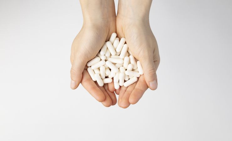 The hands of a woman hold a lot of vitamin D3 capsules, a food supplement