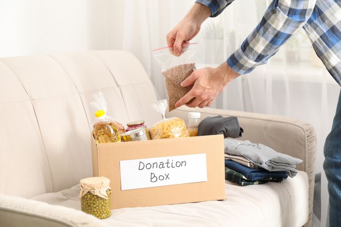 Young man puts groceries in donation box. Volunteer