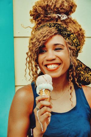 Vertical shot of happy Black female smiling with an ice cream cone in the sun