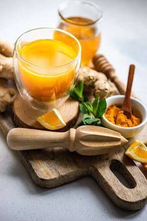 Ginger turmeric drink & ingredients on wooden cutting board