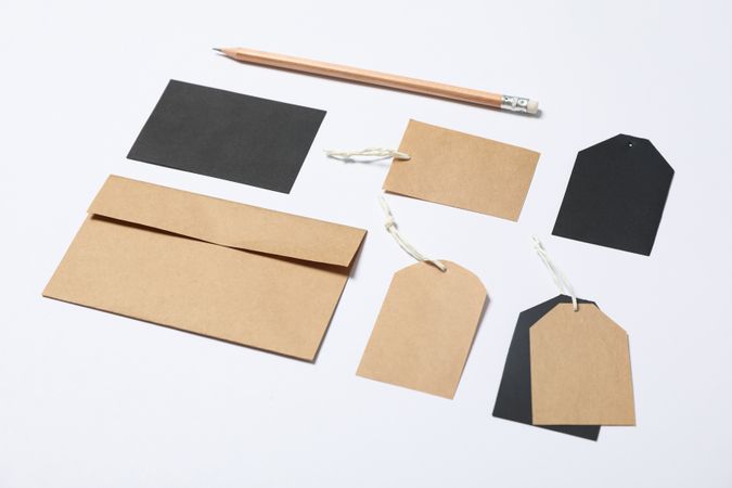 Envelope, tags and pencil on blank background, mockup