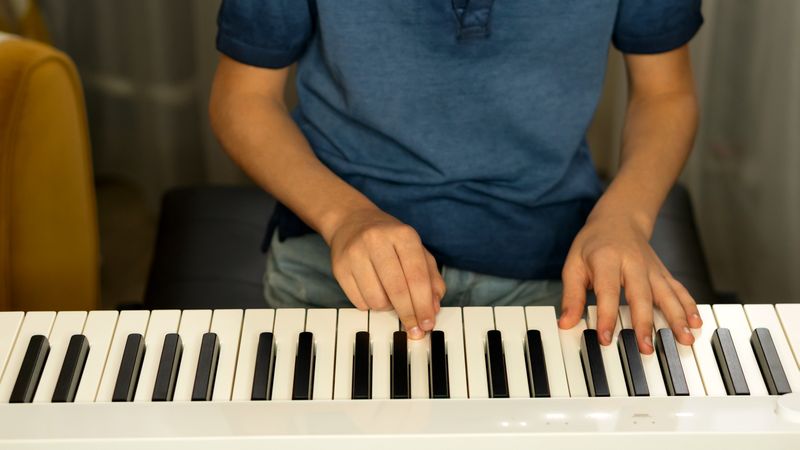 Child practicing finger placement on digital piano indoors