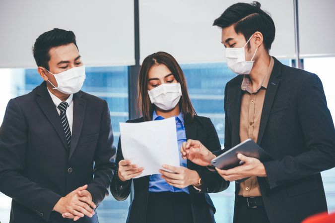 Team in Asian office working together wearing facemasks