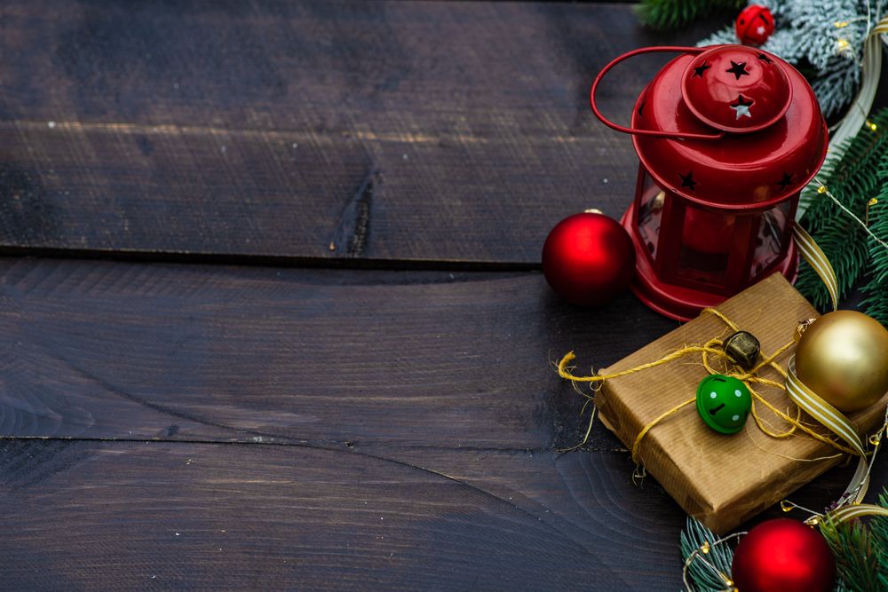Christmas gift wrapped in brown paper surrounded by baubles with light