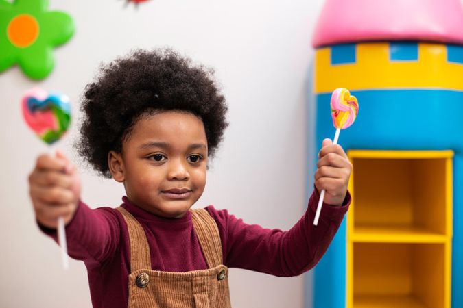 Small boy holding lollypops at kindergarden