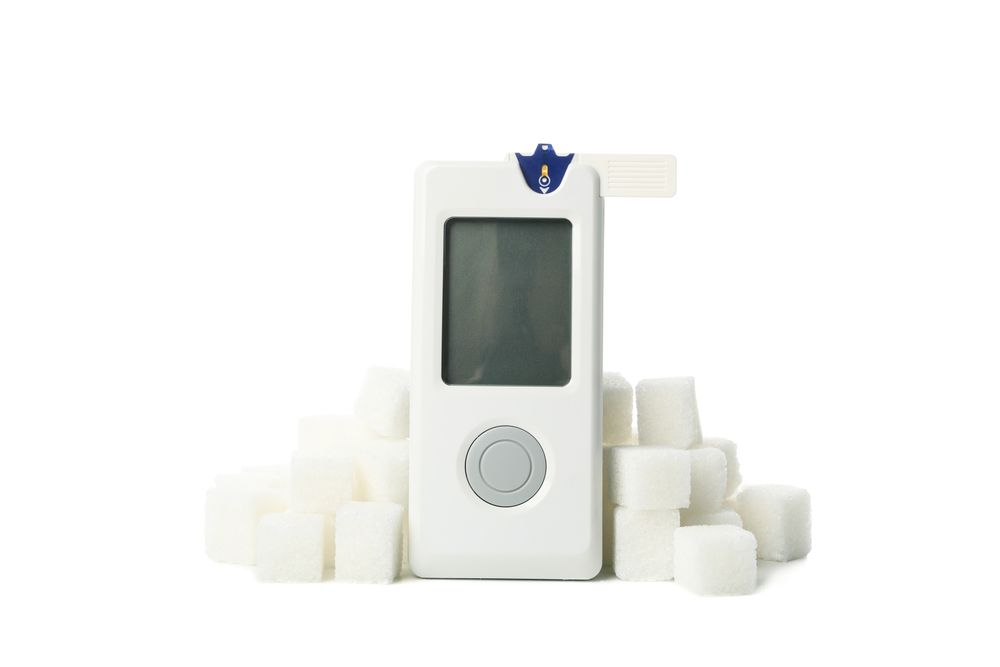 Blood glucose meter and sugar cubes isolated on blank background