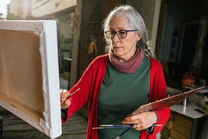 Mature woman painting on canvas in garden