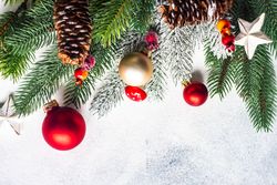 Christmas branch, pine cones, baubles and holly on grey background