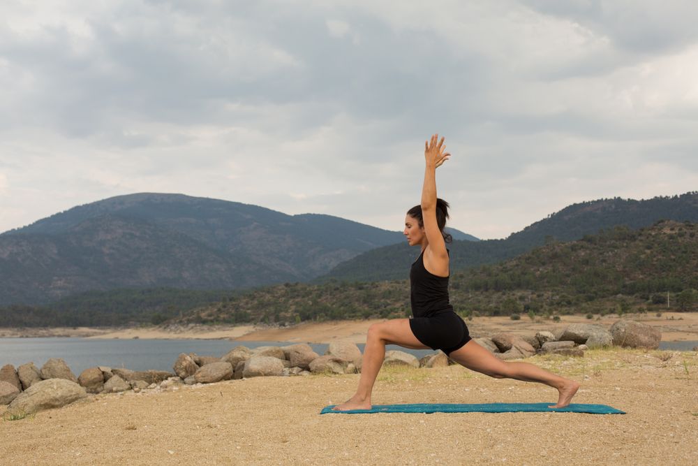 Woman practicing yoga outdoors near water
