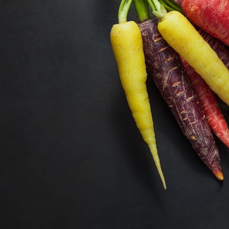 Closeup of colorful carrots and radishes on dark background