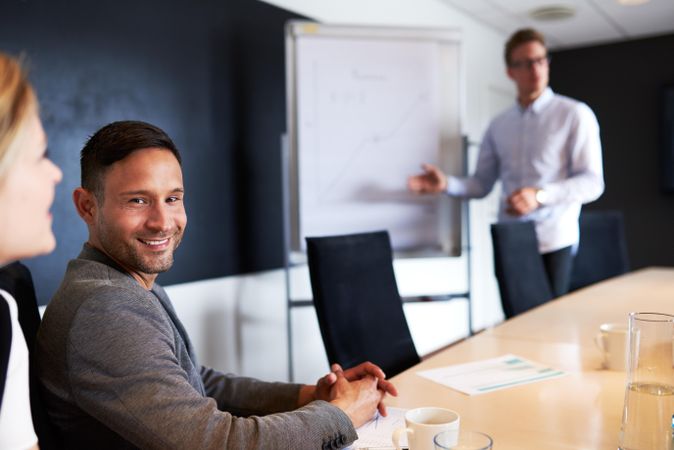 Male colleague smiling as his associate gives a presentation