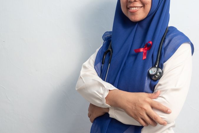 Close up Muslim Female Asian doctor or nurse wearing Red ribbons on cloth, HIV awareness concept, world AIDS day, world cancer day.