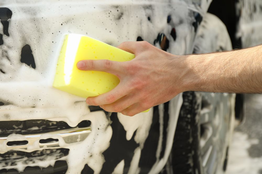 Man wipes the car with a sponge. Car wash. Clear car concept