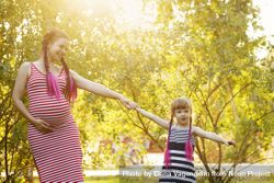 Pregnant woman holding hand of her child in a sunny park 4dprn4