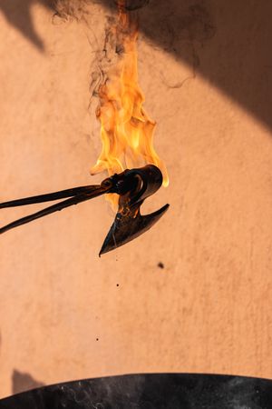 Blacksmith putting hot burning metal viking axe in water