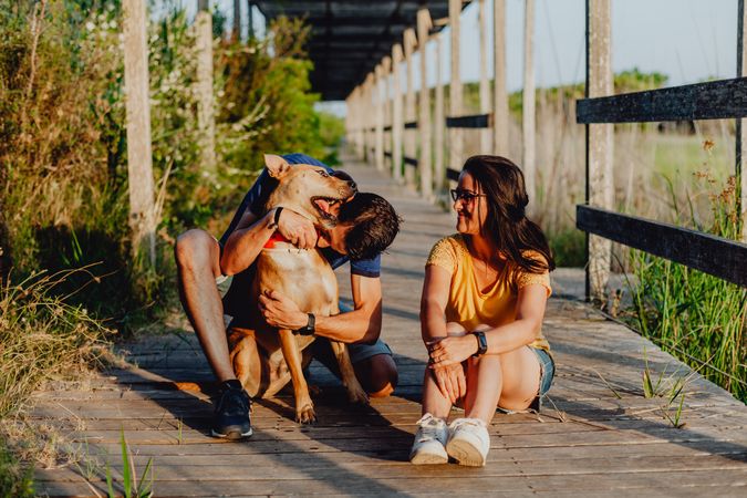Happy adult couple having fun with dog at countryside