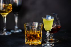 Side view of glasses of different spirits on dark background