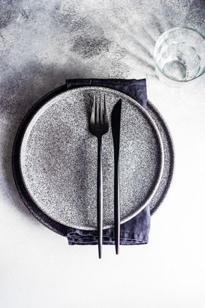 Minimalistic place setting with grey plates and dark cutlery