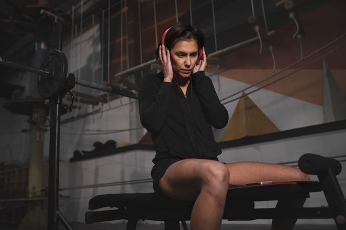 Woman with headphones and device sitting in gym