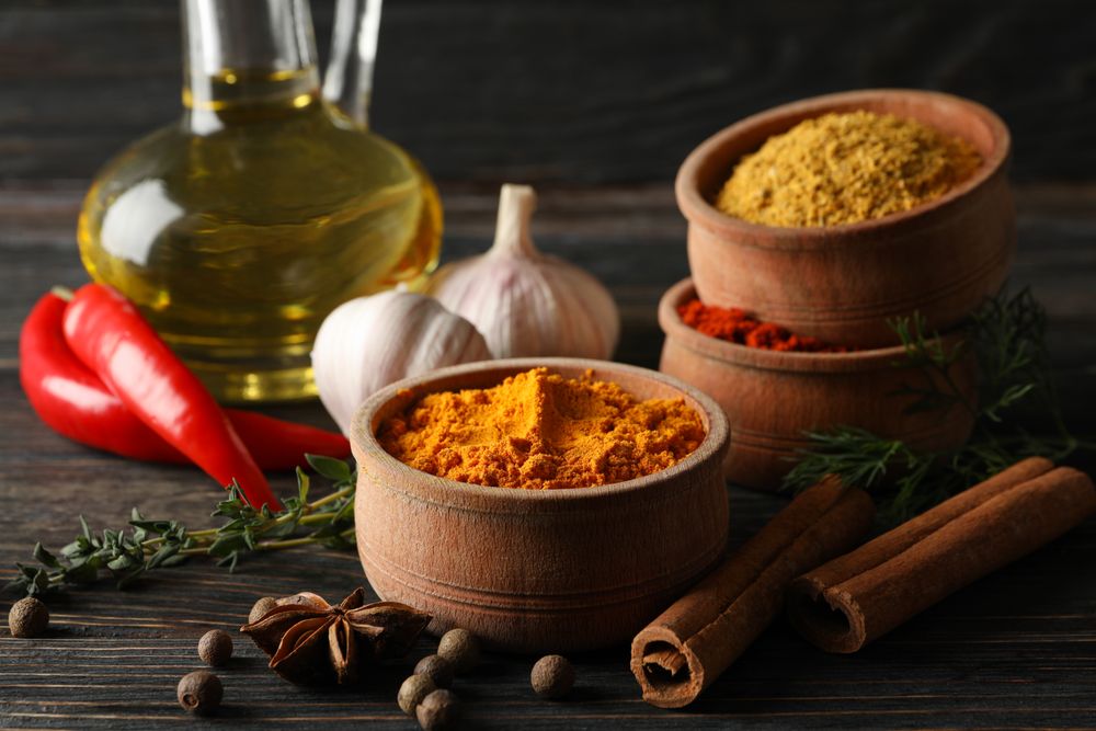 Wooden table scattered with spices and ingredients for cooking, side view